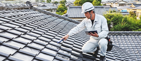 ニラスイスタッフが屋根上でタブレットを使い調査・診断している様子