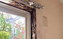 窓枠まわりの壁紙が浮き・腐食している様子