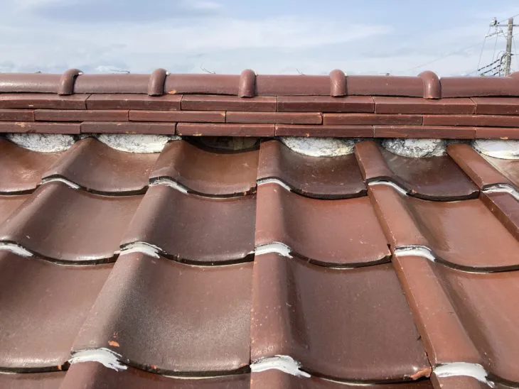 瓦屋根の最も高い位置にある「棟（むね）」の土台を保護する漆喰が、部分的に剥がれている状態でした。